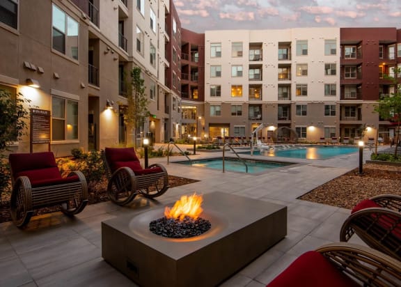 a fire pit in the middle of an apartment courtyard with a swimming pool