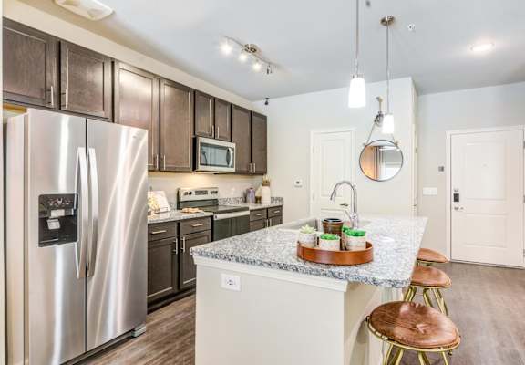 A kitchen with a refrigerator, microwave, oven, and sink.