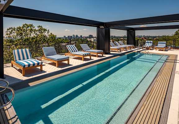 A pool surrounded by a wooden deck and lounge chairs.