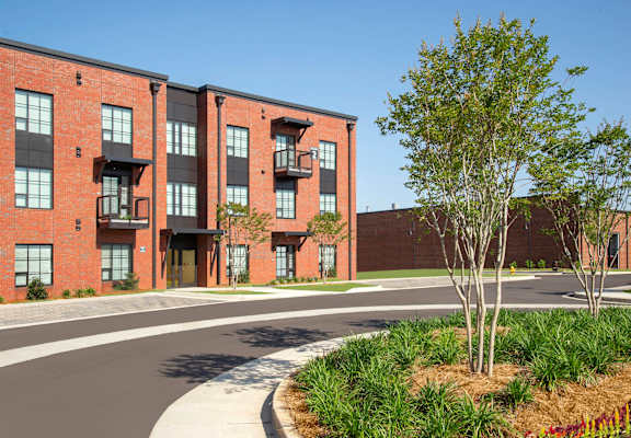 A red brick apartment building with a tree in front.