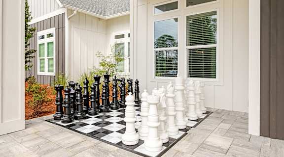 A giant chess set is set up on a patio.