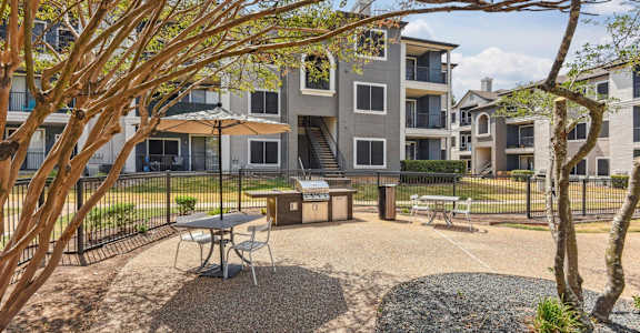 A courtyard with a picnic table surrounded by trees and apartment buildings.