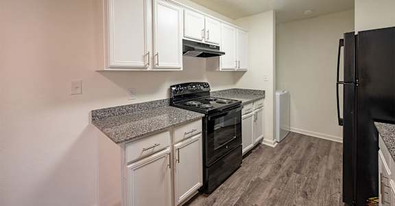 A kitchen with black appliances and white cabinets.