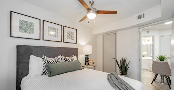 A bedroom with a large bed and a ceiling fan.