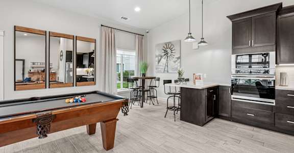 A room with a pool table and a bar area.