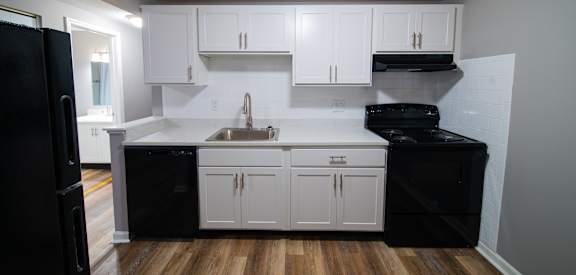 a kitchen with white cabinets and black appliances