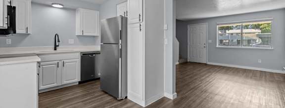 A kitchen with white cabinets and a refrigerator.
