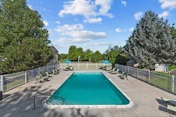 A large outdoor swimming pool surrounded by a fence and trees.