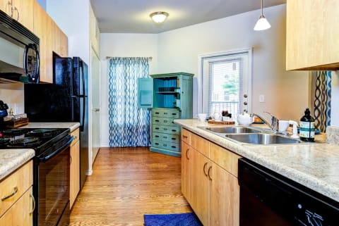 a kitchen with a black stove top oven next to a sink and a refrigerator at Villa Espada Apartments, San Antonio, Texas