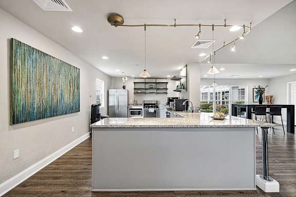A modern kitchen with a large island and a painting on the wall.