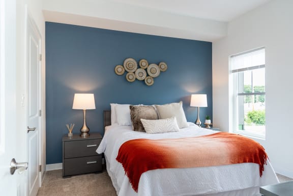 a bedroom with a bed and a blue wall and a window