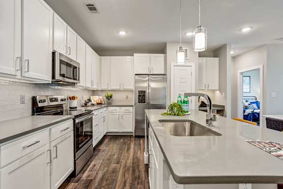 A kitchen with white cabinets and a grey counter top.