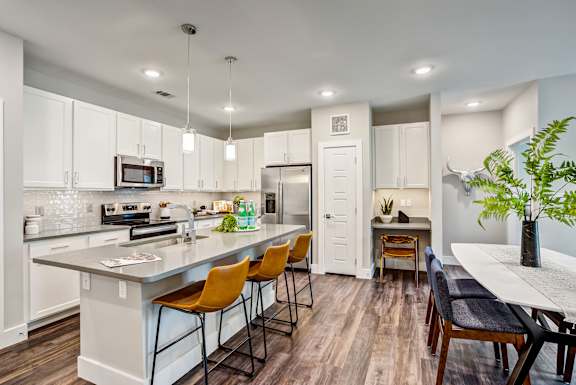 A kitchen with white cabinets and a grey counter top.