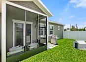 Thumbnail 6 of 7 - A house with a white fence and a green lawn.