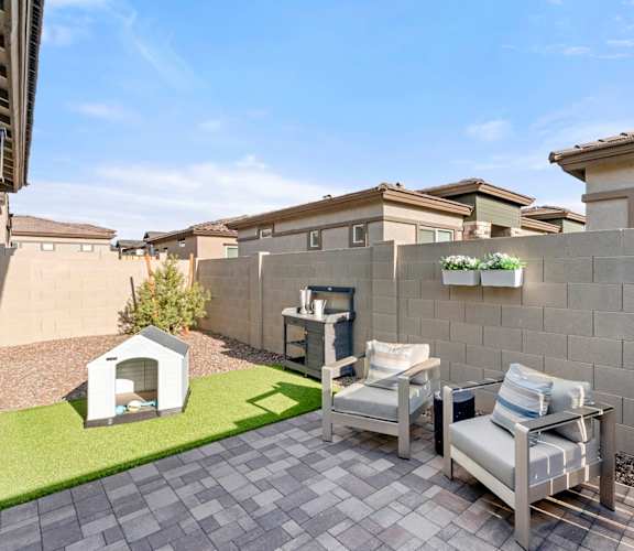 A patio with a grey couch and a small white dog house.