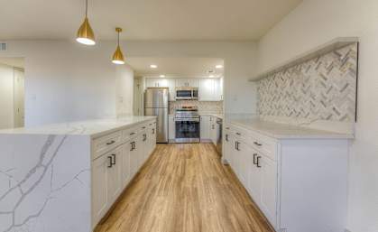 A kitchen with white cabinets and a wooden floor.at The Garden District Apartments, Germantown Tennessee