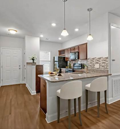 A kitchen with a bar and two chairs.