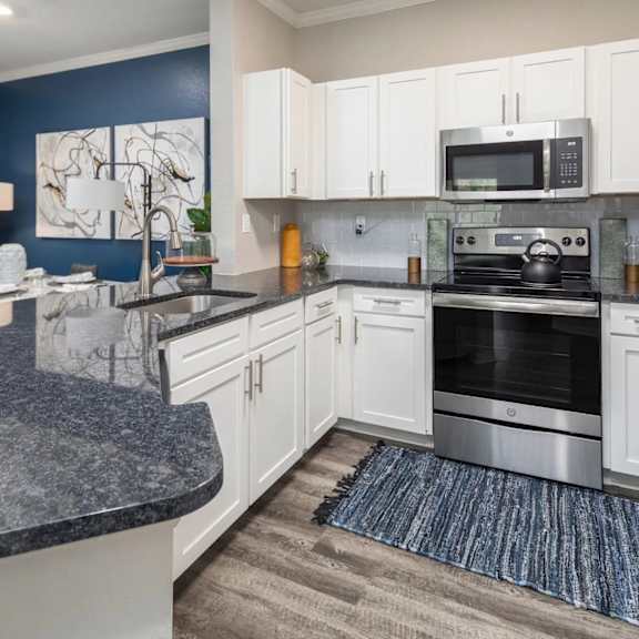 A kitchen with a granite countertop and stainless steel appliances.