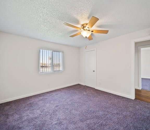 A room with a ceiling fan and a window with blinds.