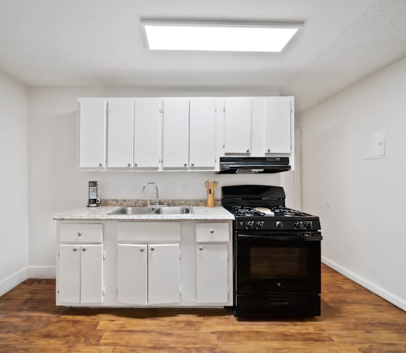 A kitchen with white cabinets and a black stove top oven.