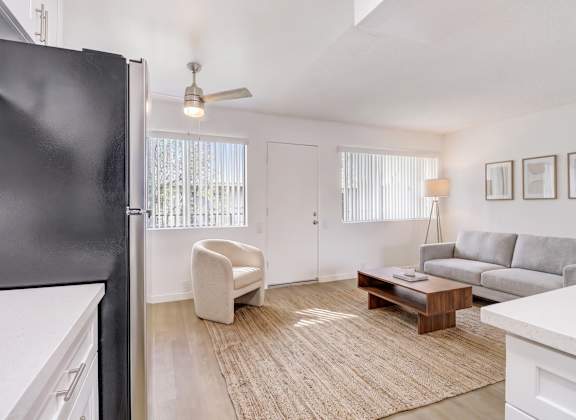 A black refrigerator is on the left in a white kitchen.