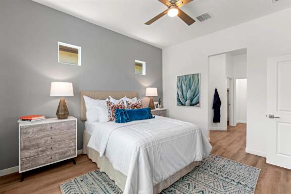 A bedroom with a white bed and a ceiling fan.