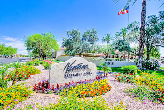 A sign for a Vine Park Apartment Homes is surrounded by flowers.