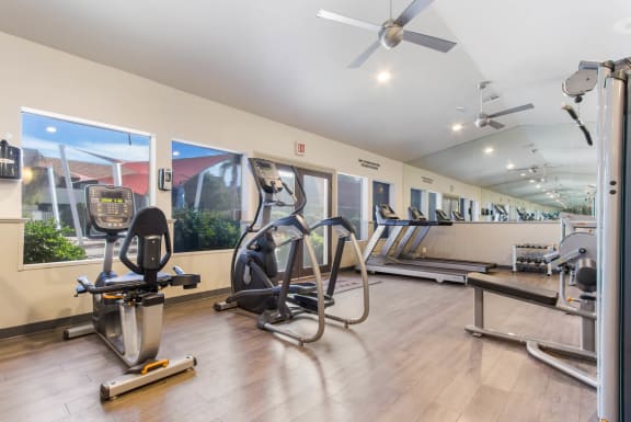 a gym with cardio machines and a large gym sign on the wall