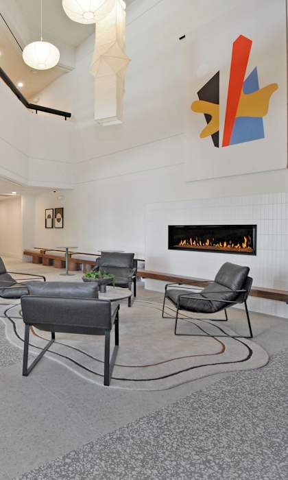 A living room with a grey carpet and a white vase.