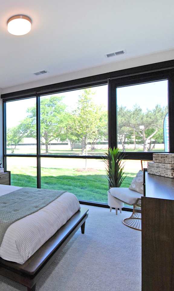 A bedroom with a large bed and a view of the backyard.