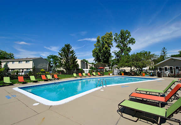 A swimming pool surrounded by lounge chairs and trees.