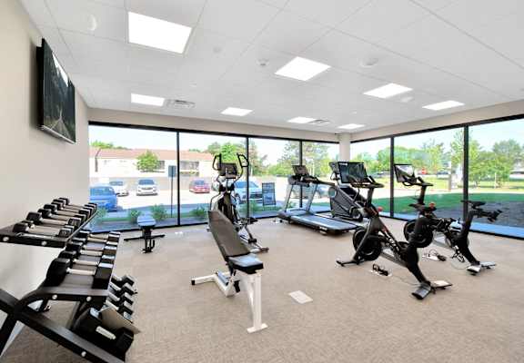 a gym with treadmills and other exercise equipment in a building with large windows