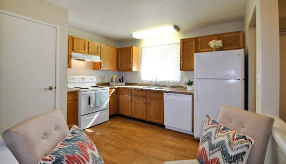 A kitchen with a white refrigerator and wooden cabinets.
