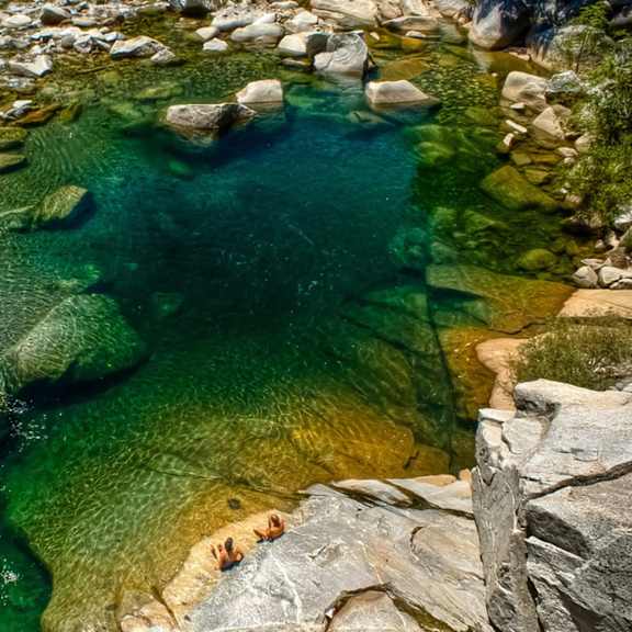 A group of people are swimming in a river surrounded by rocks.