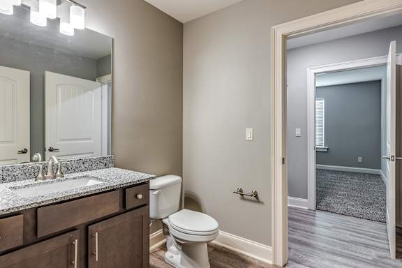 A bathroom with a toilet, sink, and mirror.