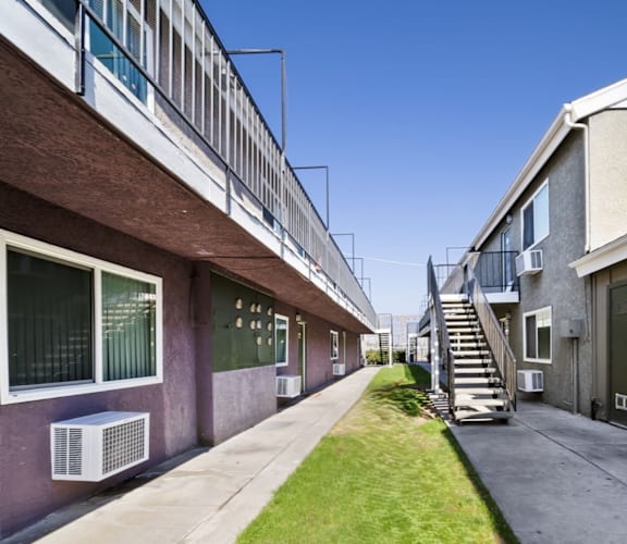 A long, narrow courtyard between two buildings with a staircase in the middle.