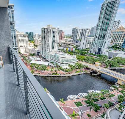 A balcony with chairs overlooks a river and cityscape.