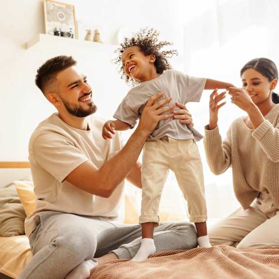 Family Playing on a Bed at Del Coronado Apartment , Mesa, Arizona
