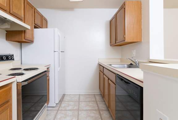 A kitchen with a white refrigerator, black oven, and black dishwasher.
