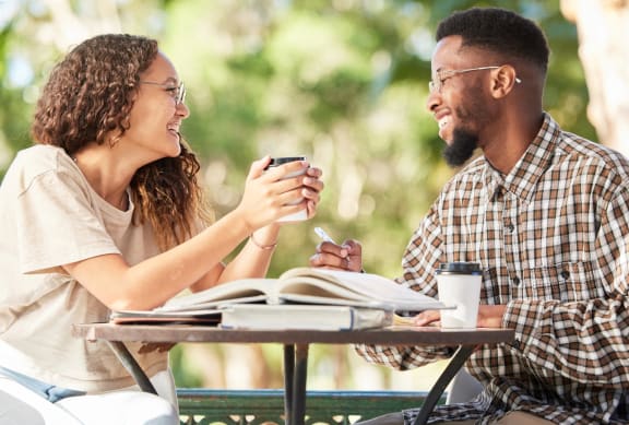 Man and Woman Sitting at Table Together and Smiling while Having Coffee