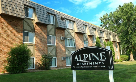an alpine apartments sign in front of a brick building