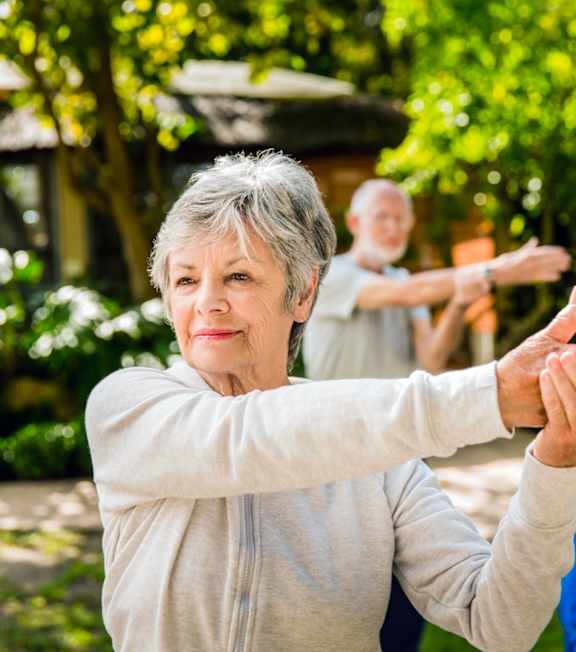 a group of elderly people exercise in a garden