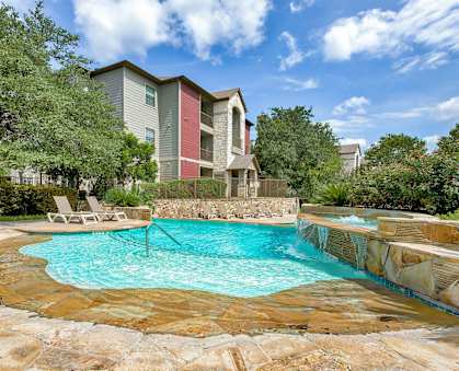 a pool surrounded by rock floors and beach chairs