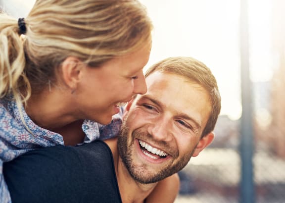 a man with a woman on his back smiling and hugging him