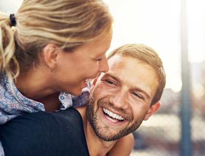 a man with a woman on his back smiling and hugging him