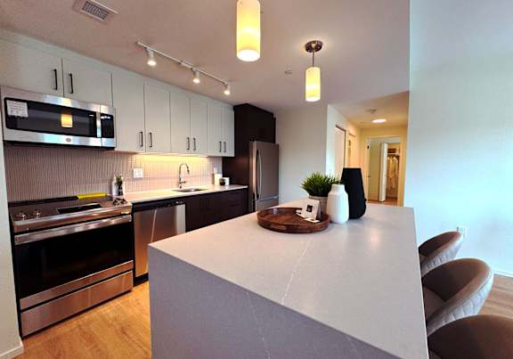 A modern kitchen with a white island and stainless steel appliances.at Imperium, Dundas Ontario