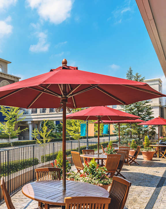 A patio with red umbrellas and wooden furniture.