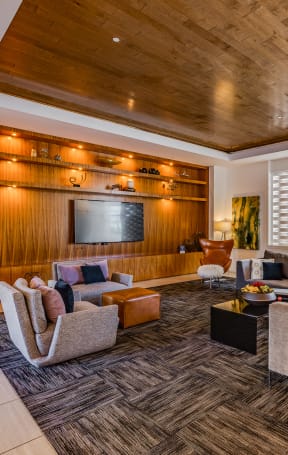 the lobby of a condo building with a lobby area with chairs and a tv