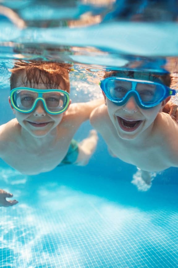 Children Smiling while Swimming Underwater Together