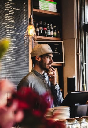 Man Standing by Checkout Counter in Coffee Shop